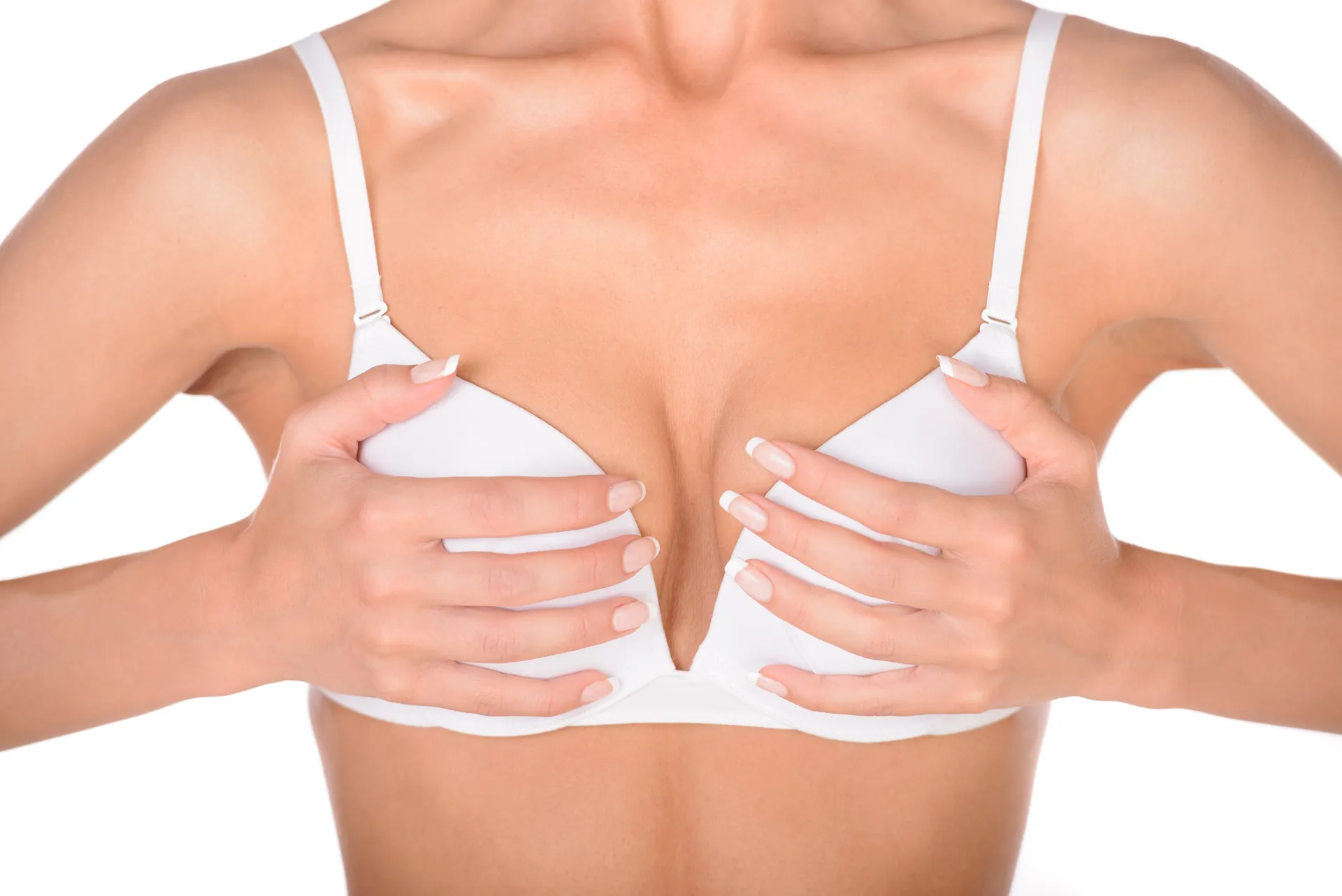Mujer con sujetador blanco que sostiene el pecho con ambas manos sobre fondo blanco, imagen simbólica sobre la contractura capsular en BONITAS Núremberg