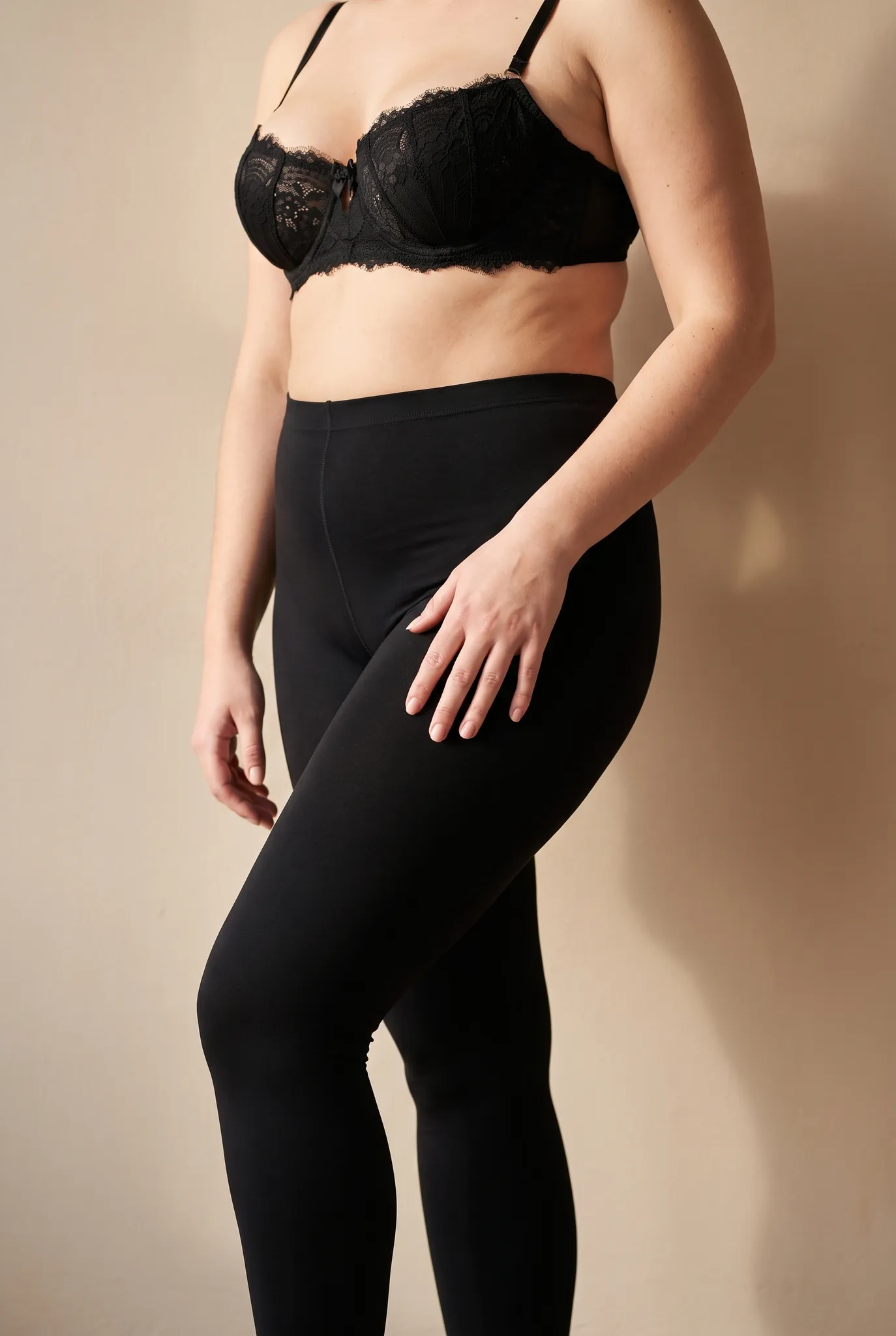 Mujer con piernas gruesas en columna con leggings de compresión negros y sujetador de encaje negro, imagen simbólica sobre los leggings de compresión para el lipedema en BONITAS Núremberg