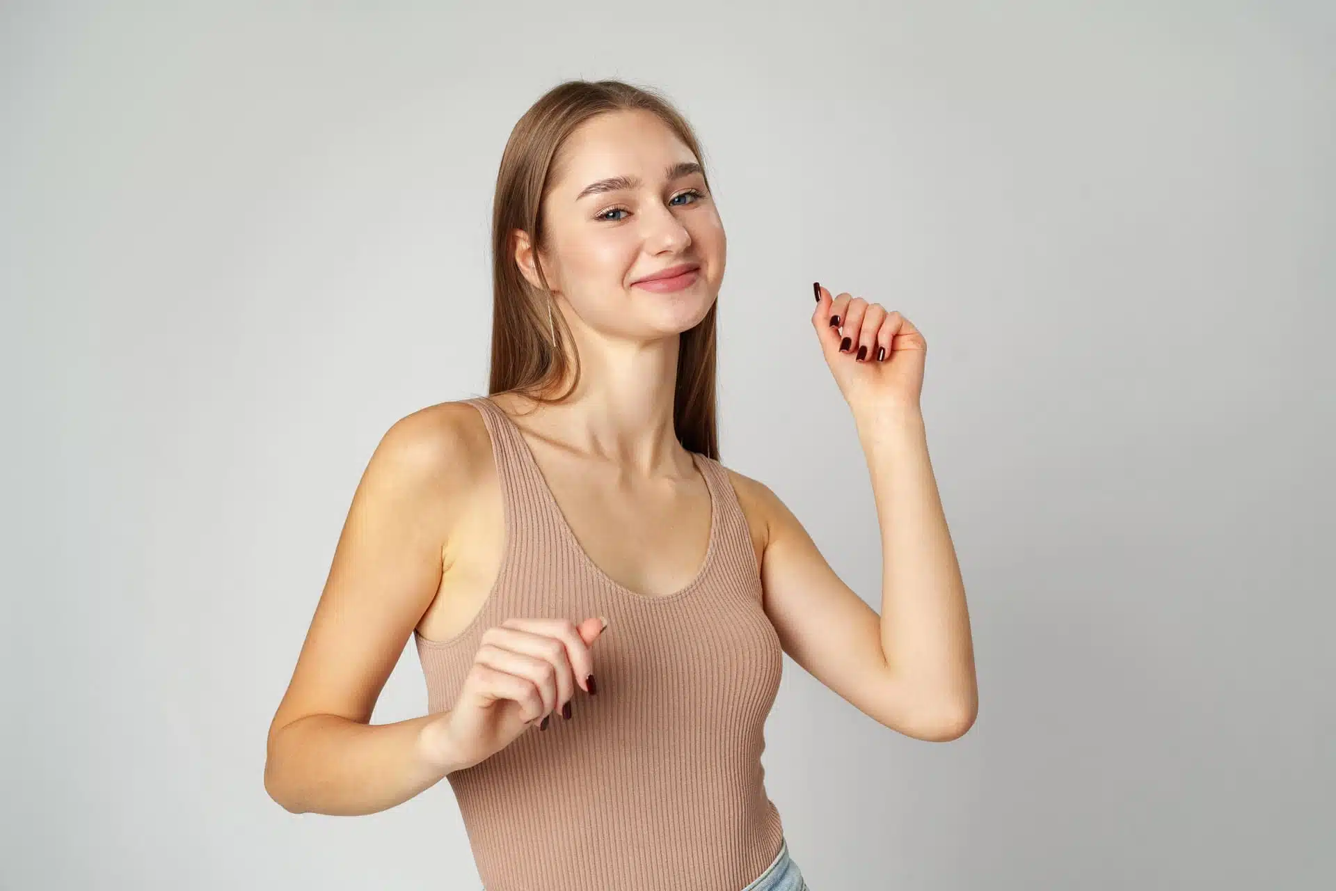 Junge Frau im beigen Ripptop lächelt seitlich mit erhobener Hand, Symbolbild zum Thema Schlupfwarzen bei BONITAS in Nürnberg