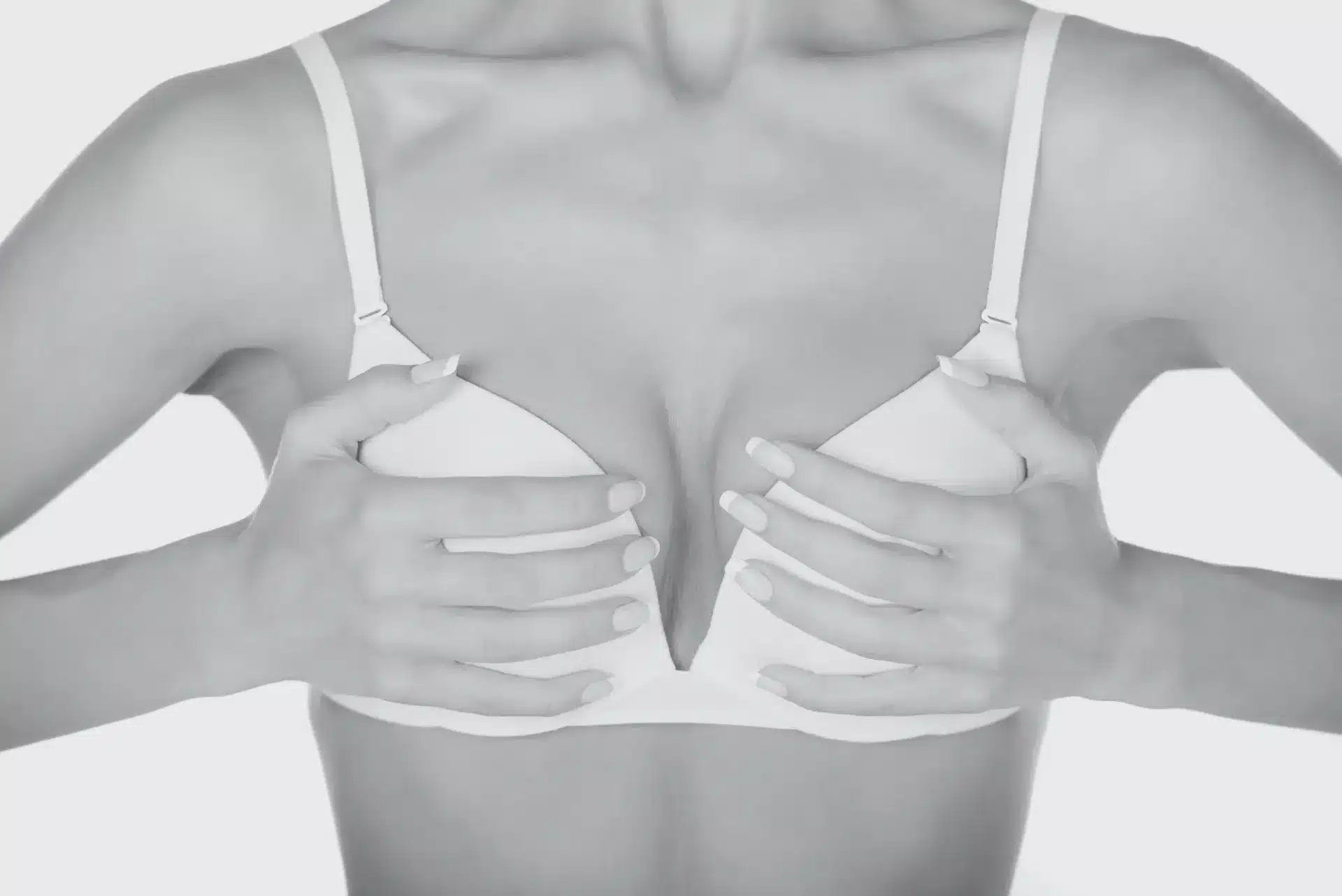 Woman in a white bra holding her breasts with both hands against a light background, symbolic image on the subject of cup size at BONITAS in Nuremberg
