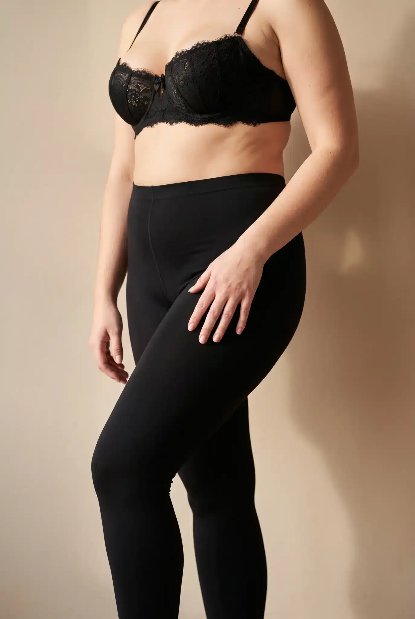 Frau mit kräftigen, säulenförmigen Beinen in schwarzen Kompressionsleggings und schwarzem Spitzen-BH, Symbolbild zum Thema Kompressionsleggings bei Lipödem bei BONITAS in Nürnberg