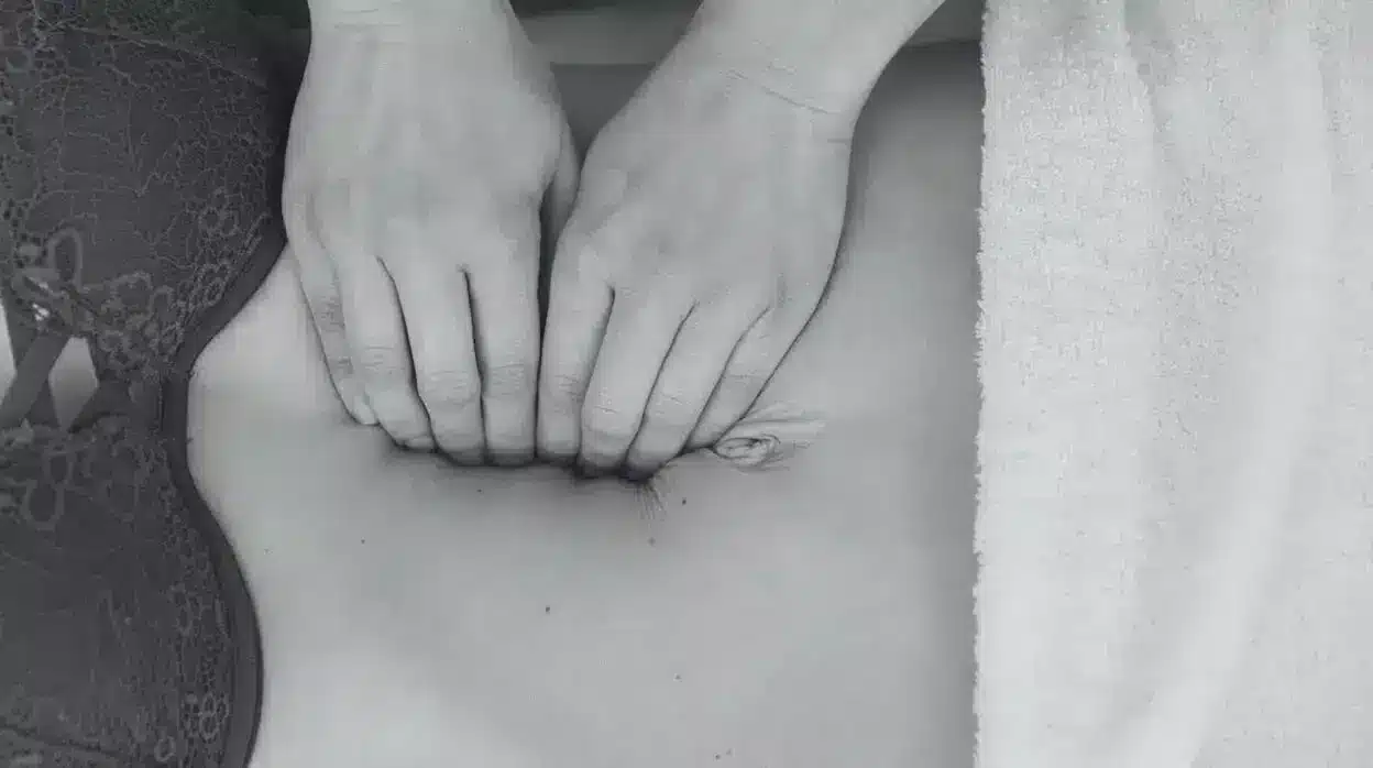 Manos sobre el abdomen de una mujer con sujetador de encaje y una toalla al lado, imagen simbólica sobre la cirugía de diástasis de rectos en BONITAS Núremberg